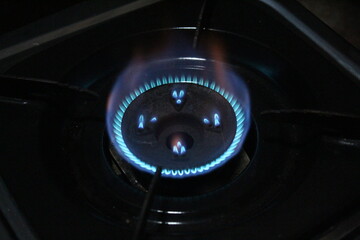 Close-up of a blue flame on a household gas stove burning steadily. The circular flame is clearly visible above the burner.