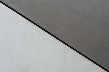 Minimalist two-tone concrete wall texture with a diagonal shadow line dividing grey shades.