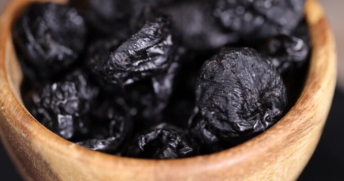 black soft dry fruits of black plums, prunes scattered on the kitchen table, black sweet seedless prunes scattered on the table
