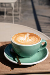 Hot latte coffee with beautiful latte art serve in green color cup