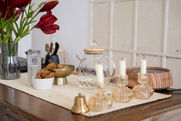 Table setting. Tea ceremony arrangement. Transparent teapot glass with tasty wholegrain snack candles bell for sound therapy flower.