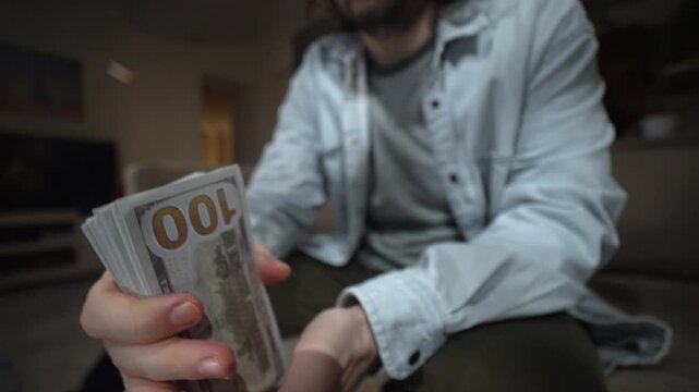 Man holding thick stack of dollar bills flipping cash toward camera. Money fanning and thumbing gesture for wealth profit income hustle success