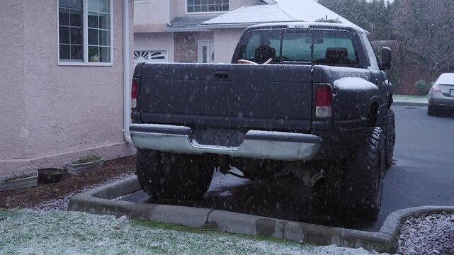 Light snow falling on a matte black pick-up truck