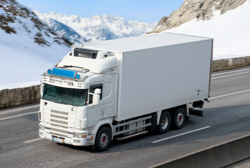 White Box Refrigerator Truck Driving through Snowy Mountain Pass in Winter