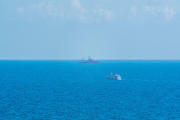 Calm blue sea with the silhouette of a large ship on the horizon