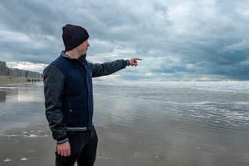 Person in beanie watches stormy ocean intensely, Guardian in jacket observes fierce waves with...