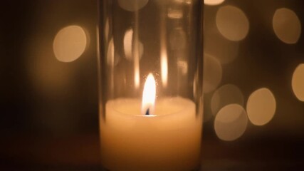 Glowing candles with burning flames create a romantic candlelight glow against a dark black background for a warm Christmas holiday celebration