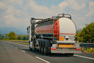 Rear View of Chemical Fuel Tanker Truck Driving on Empty Highway