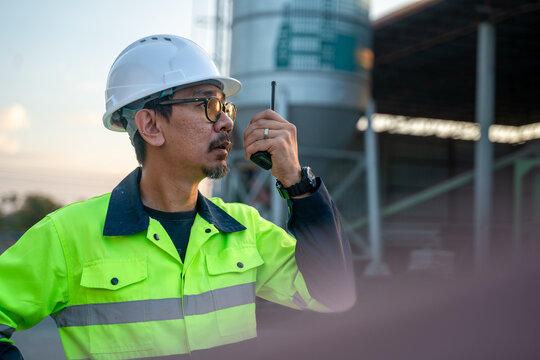 A supervisor issuing clear instructions to the team over a walkie-talkie while monitoring the cement mixing process from the ground.
