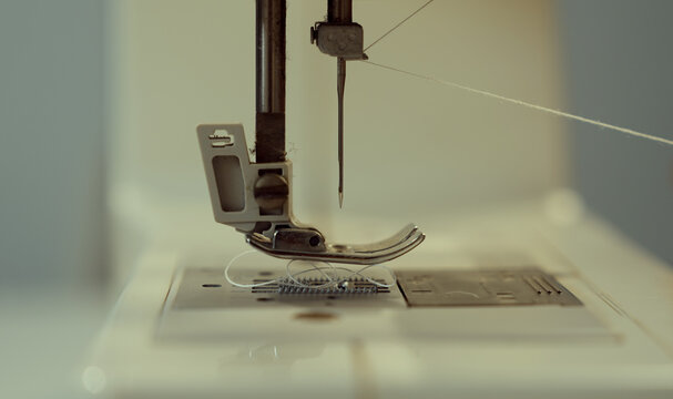 Woman clothing designer sews fabrics on a sewing machine. Needlework and handmade hobby. Selective focus.