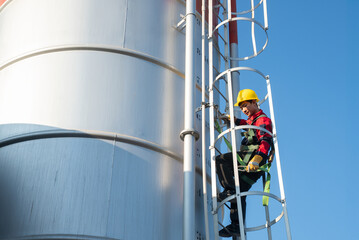 Close perspective of a worker inside ladder safety rings while ascending an industrial structure, symbolizing confined access and height safety training.