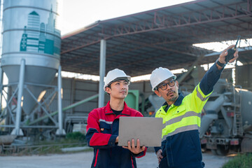 Engineers consulting laptop data beside large industrial equipment, illustrating problem solving and decision making in heavy industry.