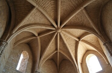 Gothic stone ceiling interior of old castle with arched windows. Ribbed vault structure, aged brickwork, classic architecture detail. Medieval building design, historic interior.