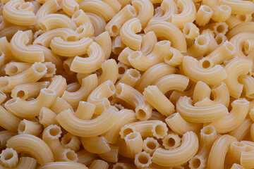 Uncooked spiral noodles with coarse semolina, Prepared elbowshaped pasta with visible semolina grains, Raw pasta arranged showcasing coarse semolina grains for cooking or display