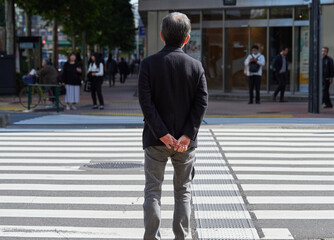 Obraz premium 東京都の都心の街の交差点で信号待ちの中年男性サラリーマンの姿