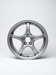 Obraz premium Close-up studio shot of a single silver five-spoke alloy car wheel on a white background, showcasing its design and finish.