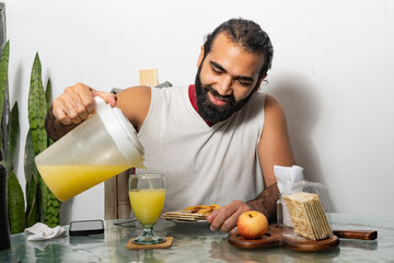Person smiling while pouring juice at breakfast table with food and smartphone
