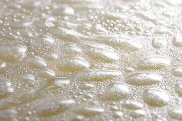 Water droplets gather on a light, smooth surface.