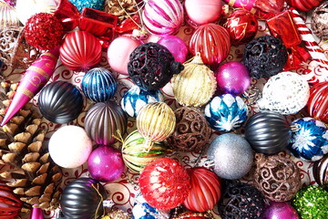 A vibrant collection of Christmas ornaments and decorations fills the scene, showcasing shiny baubles, glittering pieces, and pine cones