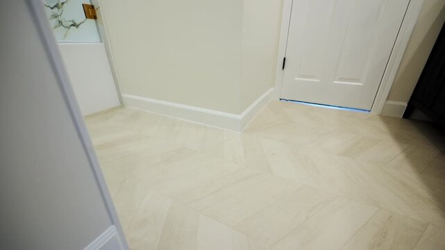 Modern bathroom floor with light-colored herringbone tiles. The bright, neutral tones and minimalist finishes create a fresh, contemporary look