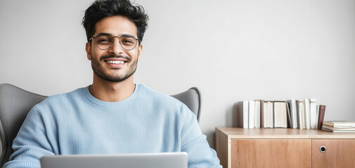 Smiling man using laptop at home office. Modern remote work lifestyle image for business, technology, freelance and online communication themes.