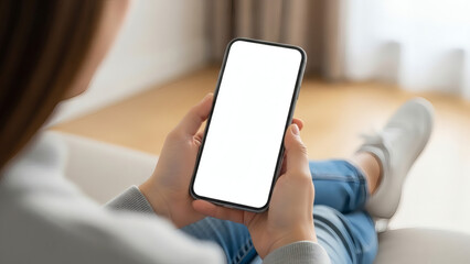 Young woman or teen girl hands holding smart phone with mockup white blank display, empty screen for social media app ads at home. Mobile applications technology concept, over shoulder close up view.