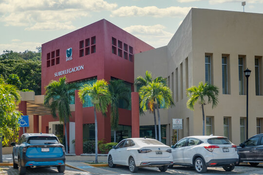 Huatulco, Oaxaca, Mexico. Dec 14, 2025. IMSS Subdelegaci&oacute;n building in Quintana Roo, Mexico, featuring modern architecture, palm trees, and an accessible parking area.