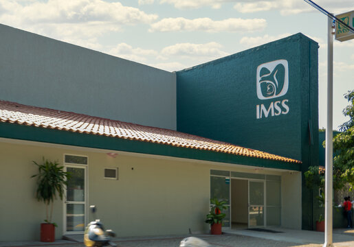Huatulco, Oaxaca, Mexico. Dec 14, 2025. Exterior view of an IMSS Unidad de Medicina Familiar (UMF) in Mexico, featuring the institution's logo on the green and beige facade with a tiled roof.