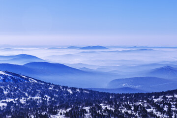 Aerial view of mountain ridges in soft fog and sky. Beautiful white blue peaks Altay mountains fades in distance. Minimal Nature abstract photo, natural winter picturesque scene, panoramic skyline.