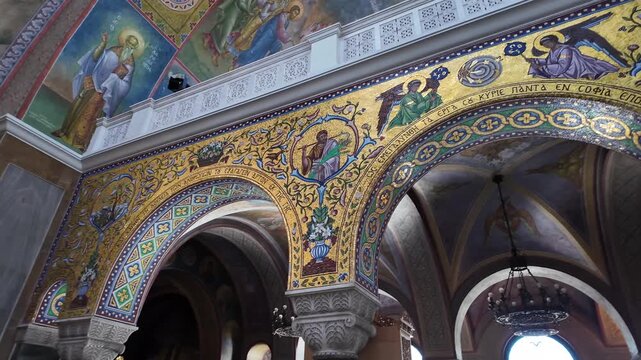 Patras,Interior of Saint Andrew's Church,Footage slides from left to right going through the colorful arches with fresco's and 2nd floor than descends slowly to the main floor at the seating area.