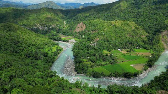 Slow gliding pan of the Chico River flowing through valleys between vibrant green trees and mountains in Bontoc, Nueva Vizcaya, Philippines, showcasing the landscape.