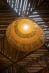 Artisanal Lamp's Warm Glow: A meticulously crafted, woven lamp casts a soft, inviting light amidst a rustic wooden ceiling. A sense of warmth and inviting illumination from the fixture