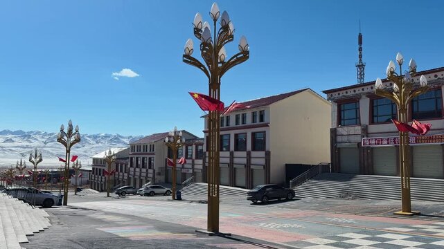 Qilian Grassland, Xining, Qinghai Province, China - A Quiet Town Street with Decorative Lamp Posts and Low Buildings Sits Against a Backdrop of Snow-covered Mountains Under a Clear Sky - Static Shot