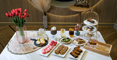 A variety of French pastries, arranged on serving plates, are prepared for sale in a pastry shop.