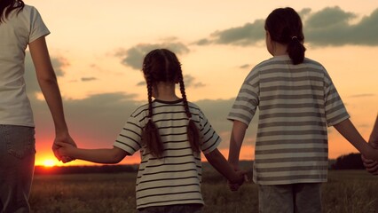 Sunset silhouette in meadow, mother father and child walking, gentle parent embrace, play outdoors...