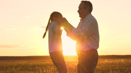 Silhouette parent and kid at sunset, father spinning little daughter, man and girl play outdoors, people in nature meadow, sky with golden sun, tiny child joy, childhood dream flight, together family