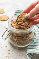 Woman hand taking homemade paw print dog treats from jar