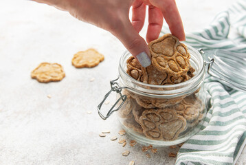 Woman hand taking homemade paw print dog treats from jar