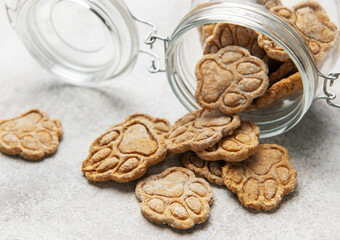 Homemade paw print dog treats spilling from jar