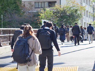 Obraz premium 朝の通勤時間の東京都内のオフィス街で歩く大勢な通勤中の男女会社員の姿