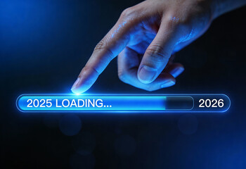Finger touching virtual loading bar from 2025 to 2026 wishing happy new year with glowing blue technology conceptual image
