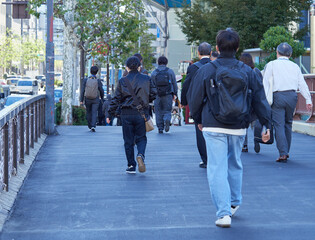 朝の通勤時間の東京都内のオフィス街で歩くサラリーマンたちの姿