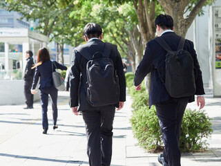昼の都心の繁華街で歩く若い女性会社員と中年男性サラリーマンの姿
