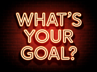 Glowing neon sign displaying the question 'what's your goal?' on a red brick wall
