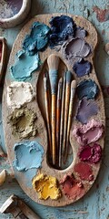 Artistic watercolor palette with vibrant painted swatches and brushes on rustic textured wooden surface for creative painting and art projects
