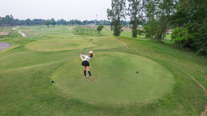 Drone view of professional female golfer playing on scenic golf course. 