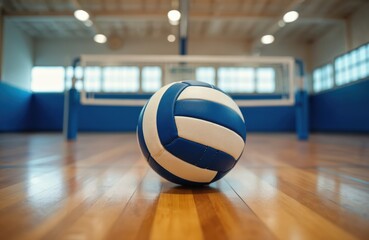 Volleyball rests on polished wooden gym floor. Blue and white ball waits near net. Indoor court reflects light, ready for game. Sport equipment for team play.