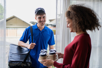 Latino delivery man in blue uniform bringing drinks to customer at home. 