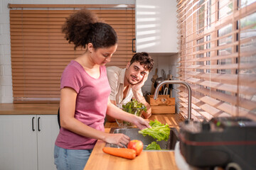 Hispanic Latina couple cleaning fresh vegetables for salad at the sink.