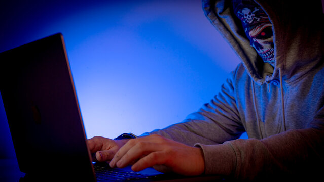 Hacker at laptop in dark room - Powered by Adobe